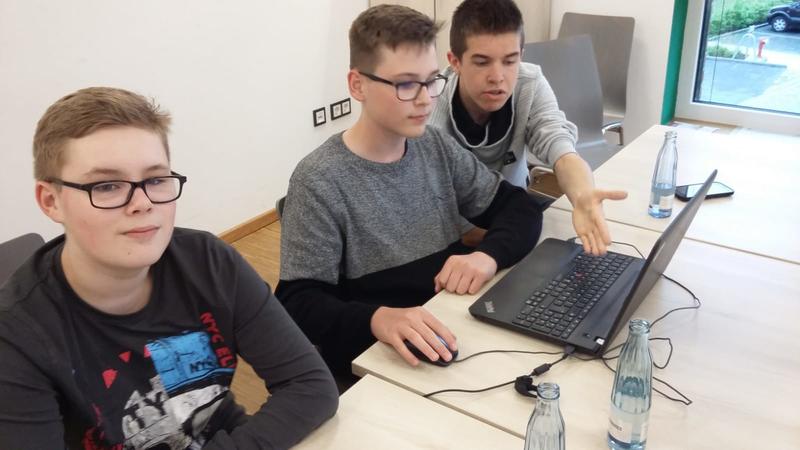 Drei Jungs im Alter von circa 14 Jahren sitzen am Tisch und suchen im Computer nach Informationen über Drogeriemärkte.