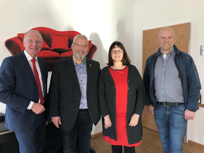 Bernd Westhal, Wolfgang Moegerle, Ingrid Klipp und Sönke Deitlaff stehen im Mehrgenerationenhaus sOfA vor einem großen Wandbild mit einem roten Sofa.